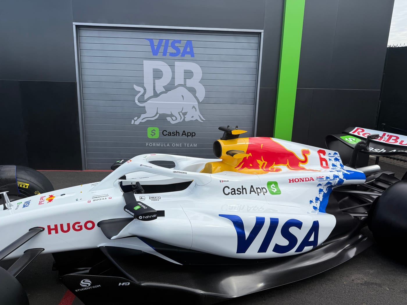 The Visa Cash App RB Formula One car in the paddock, team garage behind it